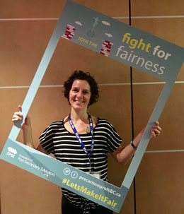 professor holding sign that reads 'fight for fairness'