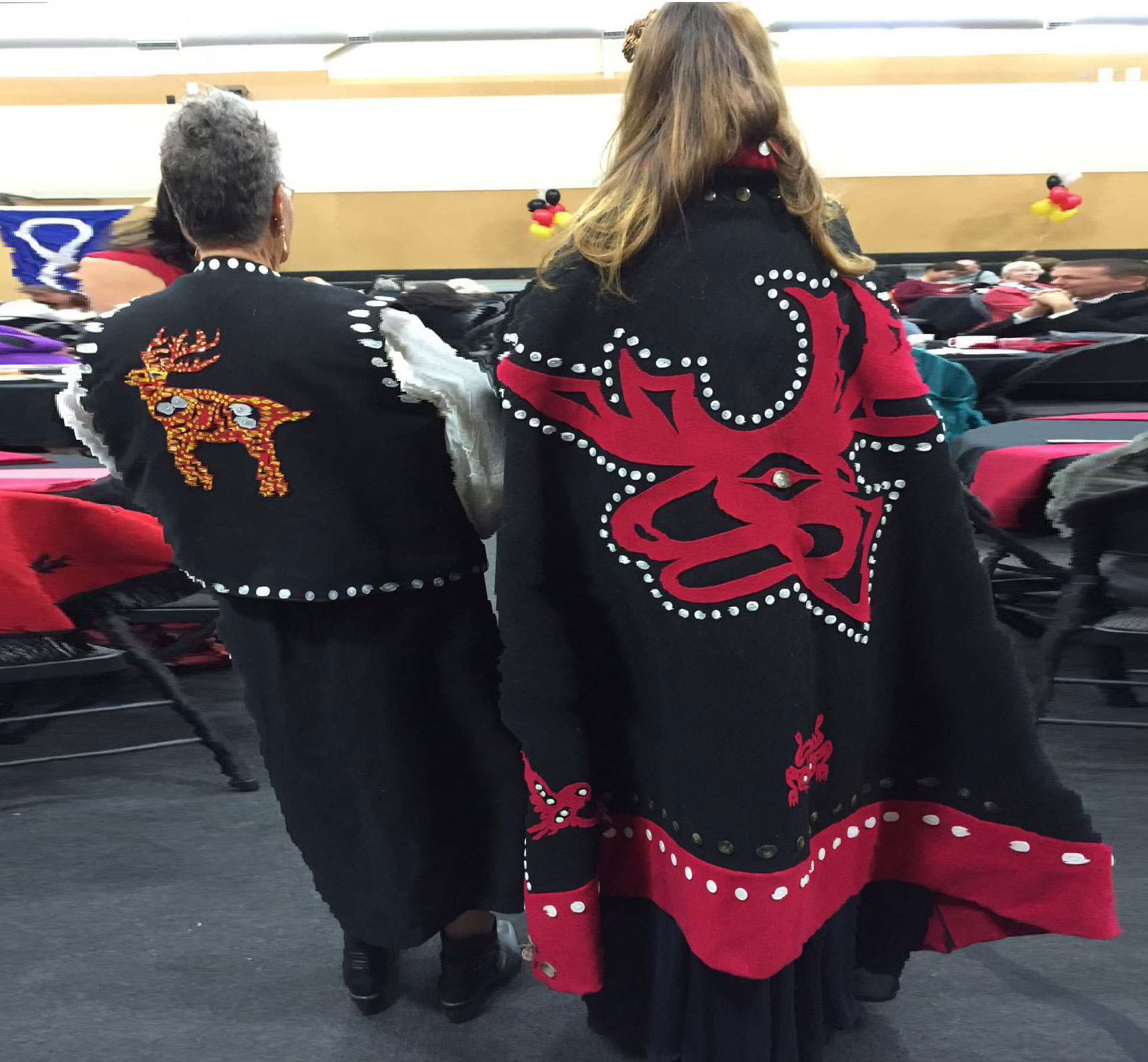 backs of two women wearing First Nations clothing
