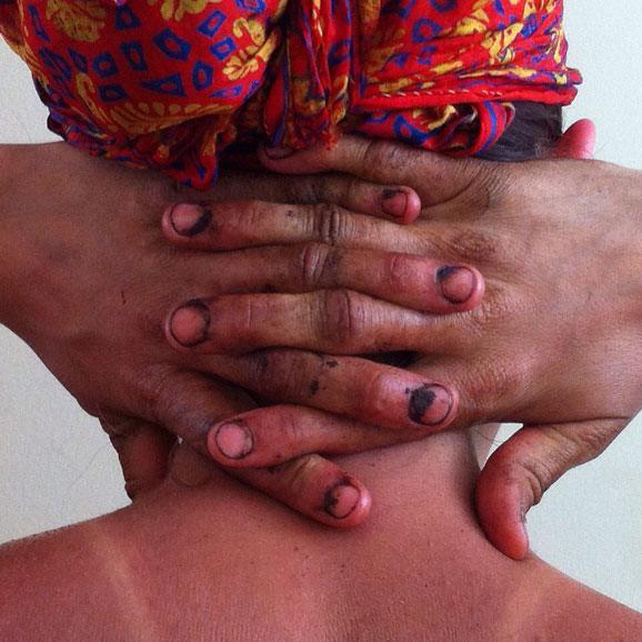 two hands with dirt in the fingernails interlaced behind a person's head