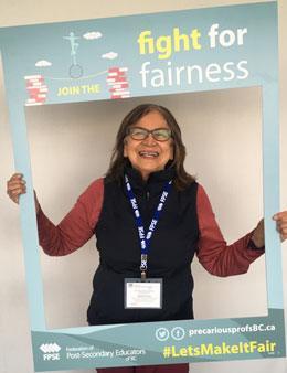 professor holding sign that reads 'fight for fairness'