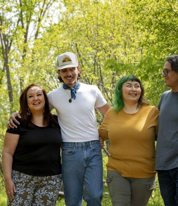 Group of indigenous people smiling and linked arms in natural setting