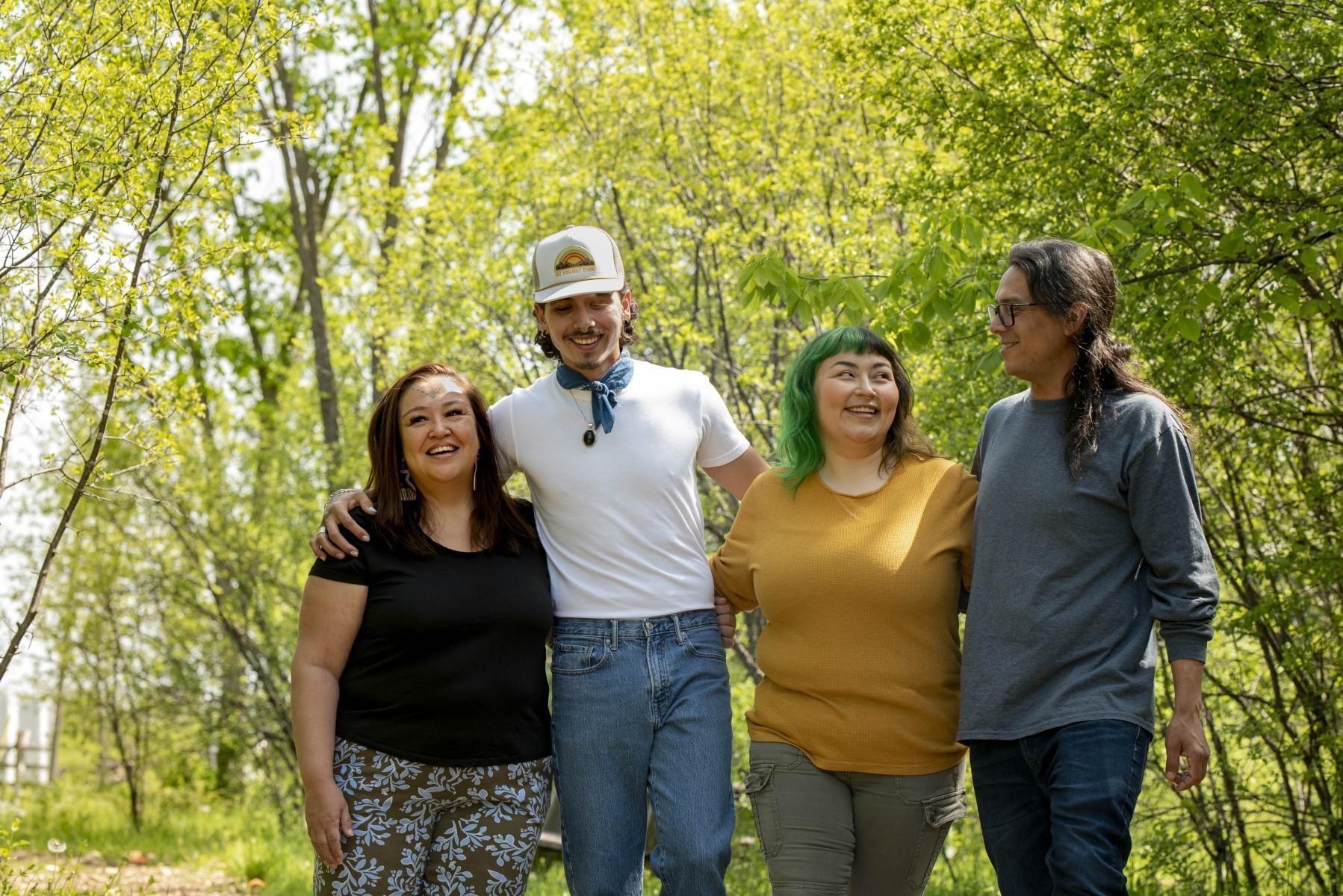Group of indigenous people smiling and linked arms in natural setting
